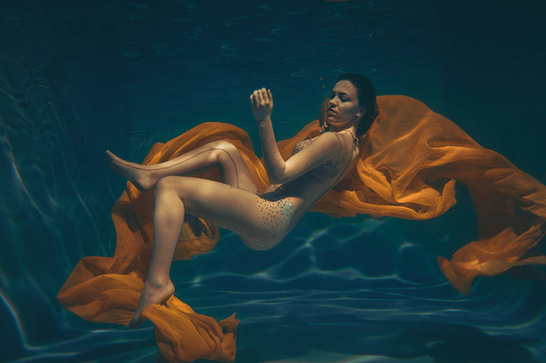 csinos sportos lány úszik víz alatti, mint a szabad búvár, a puszta színû munkaruhában egyedül - Fotó, kép