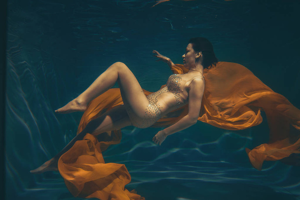 милая спортивная девушка плавает под водой как свободный ныряльщик в одних только комбинезонах
 - Фото, изображение