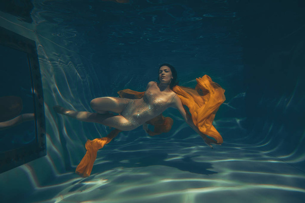 cute sporty girl swims underwater as a free diver alone - Fotó, kép
