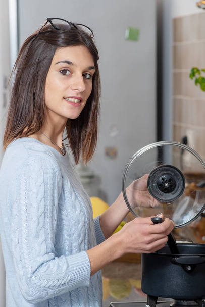 симпатичная молодая брюнетка готовит на кухне
 - Фото, изображение