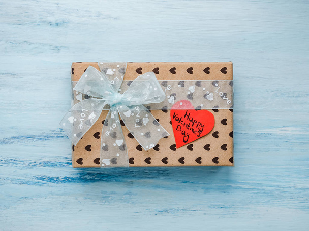 Box with a gift, tied with a ribbon, a note with sweet words of Love and tinsel in the shape of hearts. Top view, close-up, flat lay, isolated background. Preparing for Valentine's Day - Фото, изображение