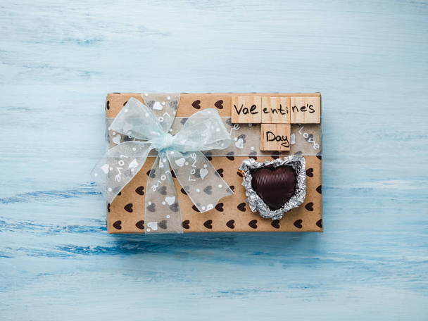 Box with a gift, tied with a ribbon, a note with sweet words of Love and tinsel in the shape of hearts. Top view, close-up, flat lay, isolated background. Preparing for Valentine's Day - Photo, Image