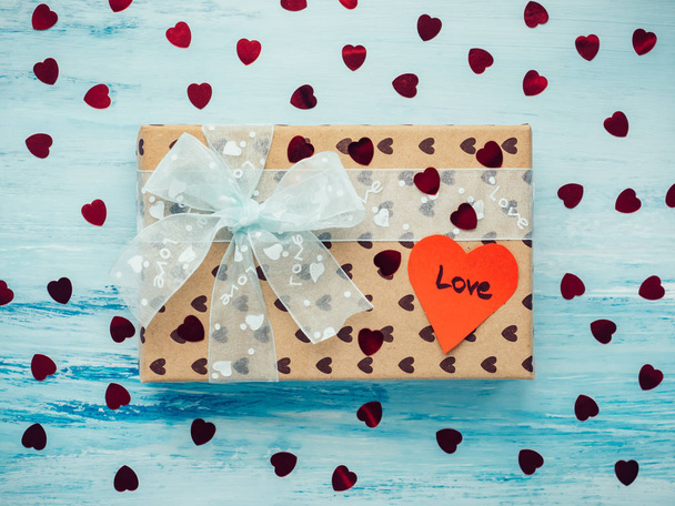 Box with a gift, tied with a ribbon, note with sweet words of love and tinsel in the shape of hearts. Close-up, flat lay, isolated. Congratulations for loved ones, relatives, friends and colleagues - Foto, Imagem
