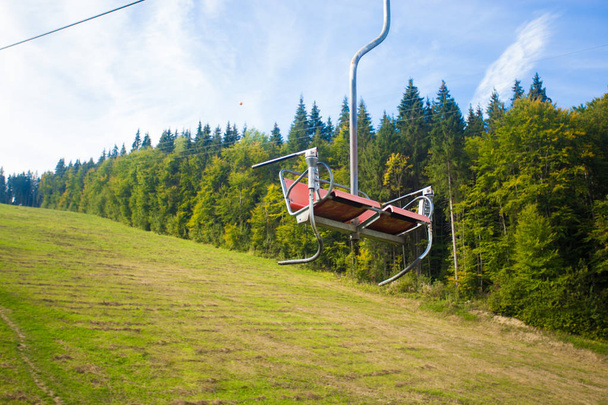 emtpy Sessellift im Skigebiet. Berge und Hügel mit im Sommer grünen Bäumen und Gras - Foto, Bild