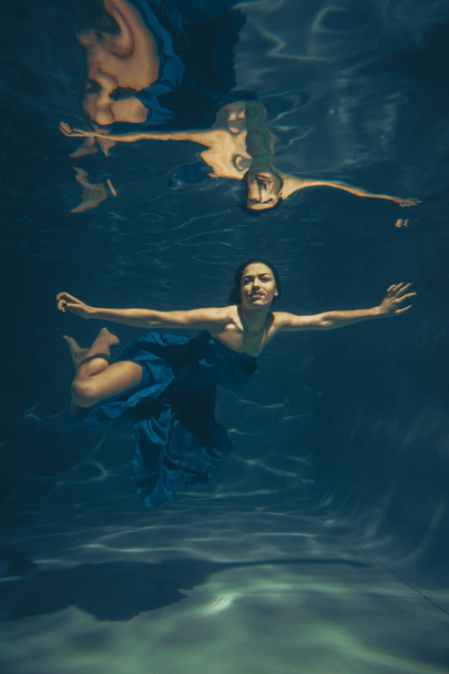 söpö urheilullinen naaras ui veden alla vapaana sukeltajana sinisessä iltapuvussa yksin
 - Valokuva, kuva