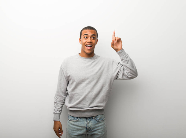 Афроамериканець людиною на фоні білої стіни, маючи намір реалізує рішення при цьому піднявши палець - Фото, зображення