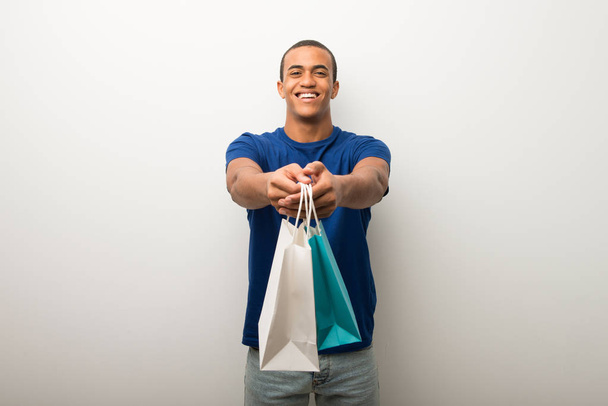 junger afrikanisch-amerikanischer Mann an weißer Wand mit vielen Einkaufstüten - Foto, Bild