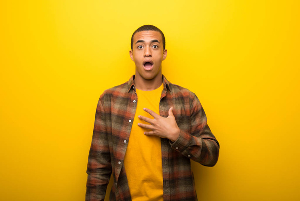 Nuori afrikkalainen amerikkalainen mies elinvoimainen keltainen tausta yllättynyt ja järkyttynyt katsoessaan oikealle
 - Valokuva, kuva