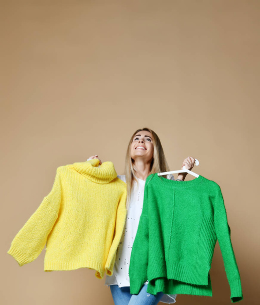 Woman shopping Christmas sale choose between two sweaters blouse green and yellow happy smiling  - Foto, immagini