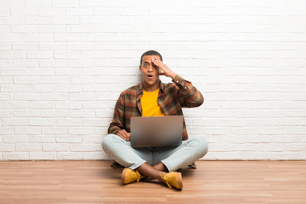 African american man sitting on the floor with his laptop has just realized something and has intending the solution - Φωτογραφία, εικόνα