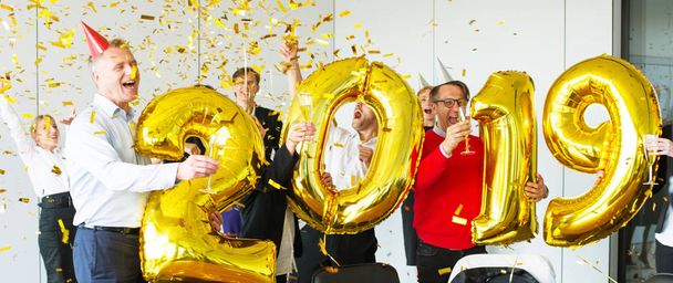 Biznesmeni świętują Nowy Rok 2019 na imprezie biurowej ze złotymi balonami - Zdjęcie, obraz