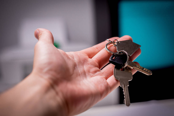 Ключі від квартири в руці. Чоловік тримає ключі зі знаком будинку в руці. Не забувайте купувати квартиру, орендувати будинок
. - Фото, зображення
