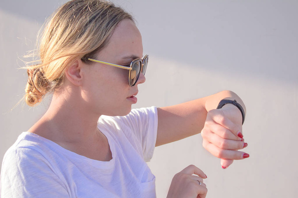 sports girl is switching on her fitbit bracelet tracker before training. - Photo, Image