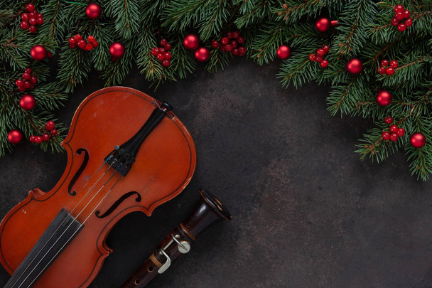 Staré housle a flétna s větve jedle s vánoční výzdobou. Vánoční a novoroční koncept. Pohled shora, close-up na tmavém pozadí betonové - Fotografie, Obrázek