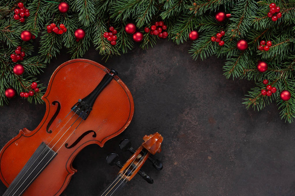 Старі скрипки та гілки ялинки з різдвяним декором. Новорічна та Різдвяна концепція. Вид зверху, крупним планом на темному бетонному фоні
 - Фото, зображення