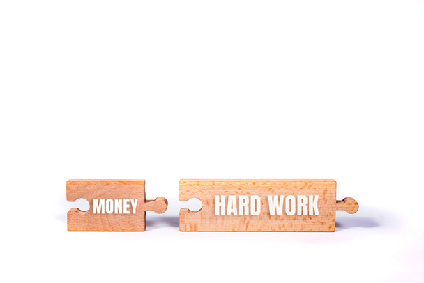 Holzpuzzle mit harter Arbeit und Geld Wort. daneben liegt ein passendes Puzzle. das Konzept der persönlichen Entwicklung, Geld kann durch harte Arbeit erreicht werden. - Foto, Bild