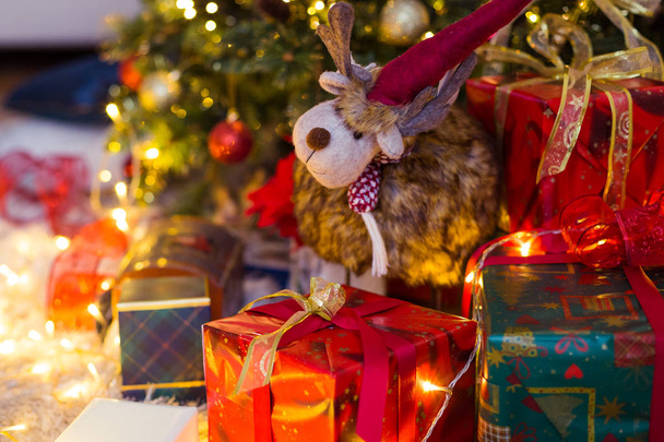 Oyuncak geyik hediyeler ve Noel ağacı arka planda arasında.  - Fotoğraf, Görsel