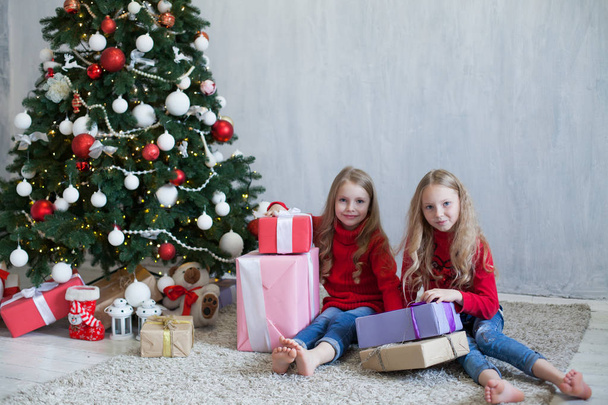 duas meninas pequenas loira em vestido vermelho em presentes de Natal ano novo
 - Foto, Imagem
