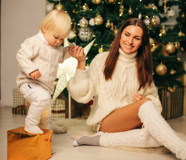 holiday Christmas photo of small cute boy and his beautiful mother playing with toys in decorated home - Fotoğraf, Görsel
