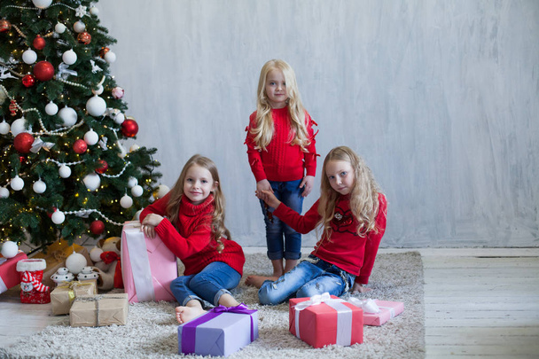 drei kleine Mädchen Blondine in rotem Kleid bei Weihnachtsgeschenken Neujahr Urlaub - Foto, Bild