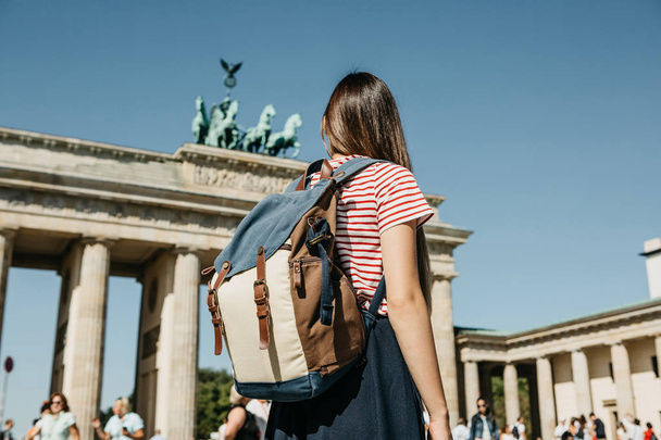 Турист или студент с рюкзаком у Бранденбургских ворот в Берлине в Германии, смотрит на достопримечательности
. - Фото, изображение