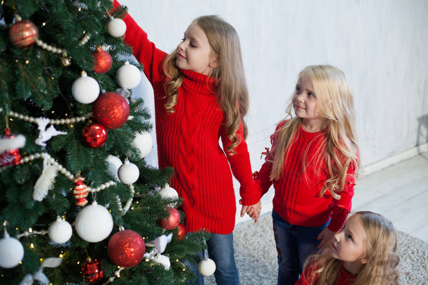 three small girls blonde in red dress at Christmas gifts new year holiday - Photo, Image