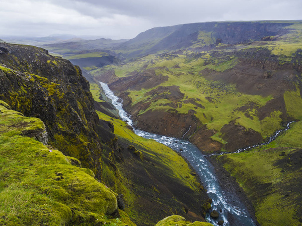Valle del paisaje del río Fossa con arroyo de agua azul y verdes colinas y acantilados cubiertos de musgo, en el sur de Islandia, cielo malhumorado de verano
 - Foto, imagen