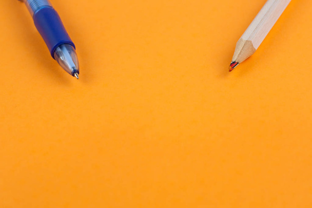 Multi color blue transparent ballpoint and wooden pencil on background of orange paper with copy space - Photo, image