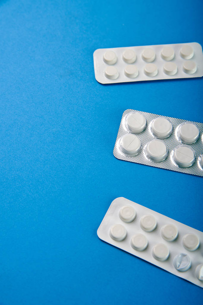 Kahdenlaisia yksinkertaisia valkoisia pillereitä apteekista kirkkaan sinisellä taustapöydällä. Minimalistinen lääkkeiden, apteekkien mainonta. Lääkkeet eri sairauksien hoitoon
. - Valokuva, kuva