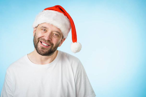 Bearded man wearing santa claus hat portrait, on blue with copy space. Christmes time. - Valokuva, kuva