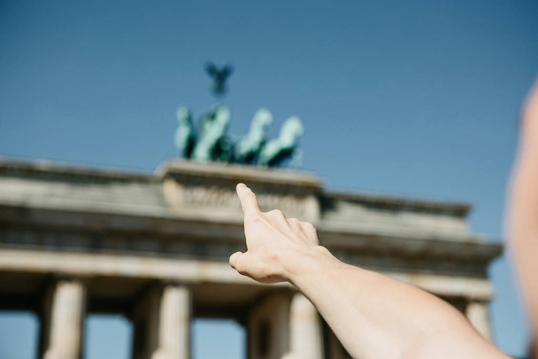 Toeristische of man toont zijn hand op de Brandenburger Tor in Berlijn - Foto, afbeelding