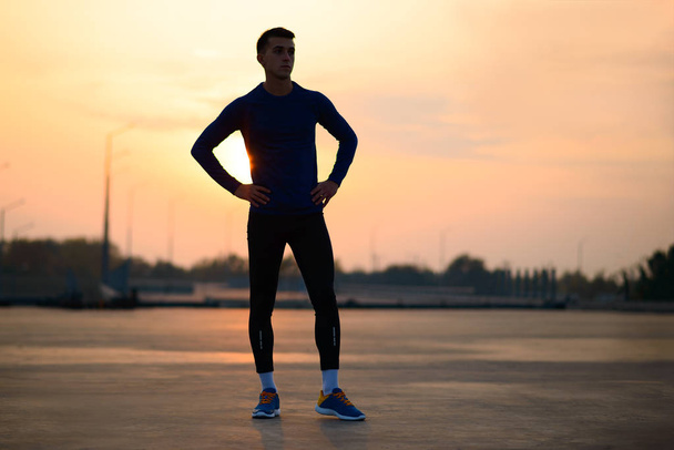 Young Male Runner Resting after Run at Sunset. Healthy Lifestyle and Sport Concept. - Photo, Image