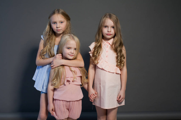drie mooie meisjes zusters portret mode grijze achtergrond - Foto, afbeelding