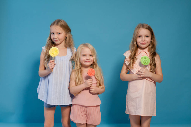 three beautiful young girls and sweet candy lollipops - Photo, Image