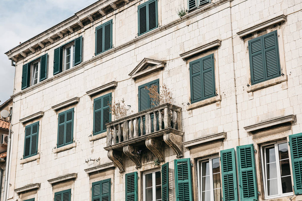 The facade of an ordinary old building with windows and a balcony in Montenegro. - Foto, afbeelding