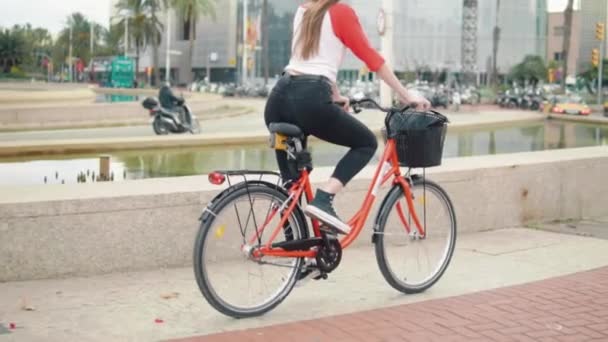 young woman or girl riding bicycle pedalling next to palm trees - Footage, Video