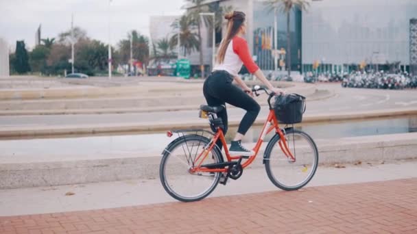 young woman or girl riding bicycle pedalling next to palm trees - Footage, Video