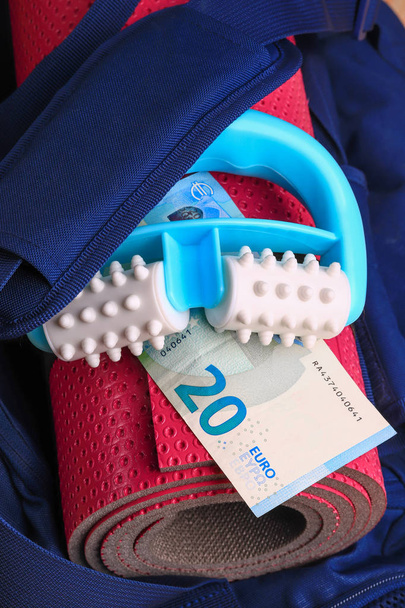 Růžový jóga mat a tělo masér v modrý batoh s peníze Euro bankovek. Sada pro fitness a masáže. Placené služby a skupinový trénink - Fotografie, Obrázek