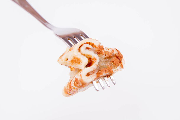 Pancakes stuffed with braised apples sprinkled with cinnamon on a fork - Φωτογραφία, εικόνα