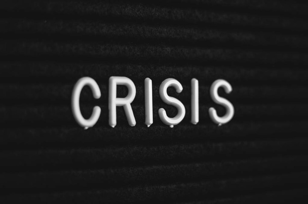 Слово кризис написано на доске объявлений. Белые буквы на черном фоне
 - Фото, изображение