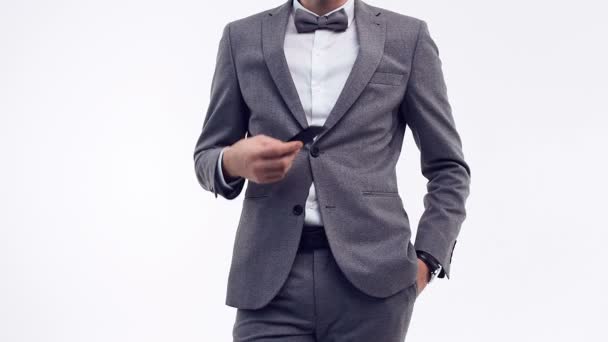 Nahaufnahme Porträt eines jungen selbstbewussten Geschäftsmannes mit einem modischen grauen Anzug, der ein Telefon isoliert auf weißem Studiohintergrund hält - Filmmaterial, Video