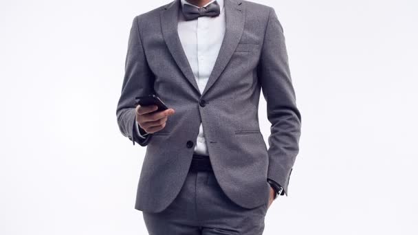 Lähikuva muotokuva nuori luottavainen liikemies muoti harmaa puku pitämällä puhelimen eristetty valkoinen studio tausta
 - Materiaali, video