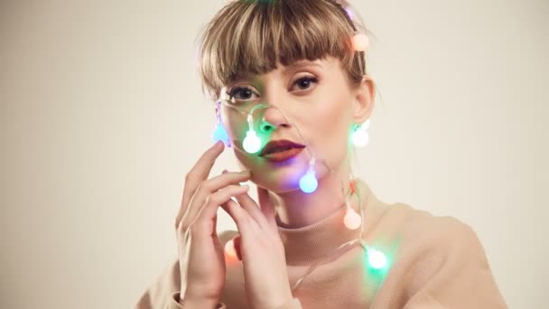 Fashion bright portrait of beautiful blond woman with christmas lights on the head. Studio shoot. - Footage, Video