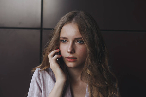 Unhappy teen girl looks at her smartphone experiencing anxiety and sad. - Photo, Image