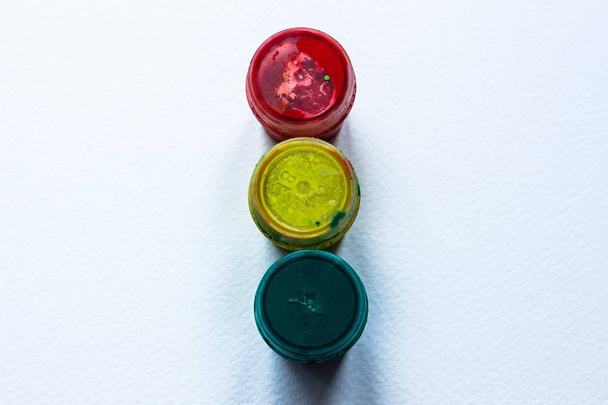 Three jars of yellow, red and green paint are on a white background in the form of a traffic light. A good learning abstraction. - Foto, afbeelding