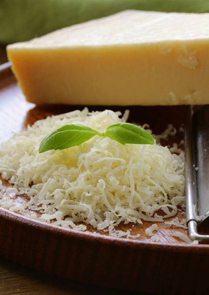 geraspte Parmezaanse kaas en metaal rasp op houten plaat - Foto, afbeelding