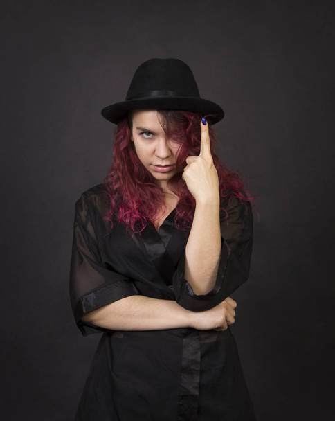 Emotional brunette in a hat with long hair posing in the Studio.Isolated images on a dark background. - Foto, Bild