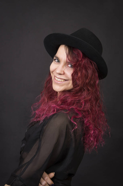 Emotional brunette in a hat with long hair posing in the Studio.Isolated images on a dark background. - Foto, afbeelding
