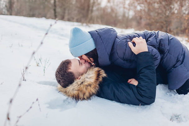Hermosa pareja amorosa tumbada en la nieve y besándose en el bosque de invierno. La gente se divierte al aire libre. Relaciones románticas
 - Foto, Imagen
