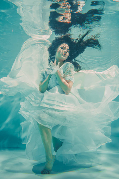 sexy novia joven nadando bajo el agua en vestido de novia blanco, medias y guantes
 - Foto, imagen